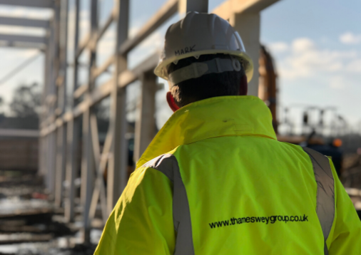 Rear view image of construction worker, wearing a high visibility jacket and safety hat.