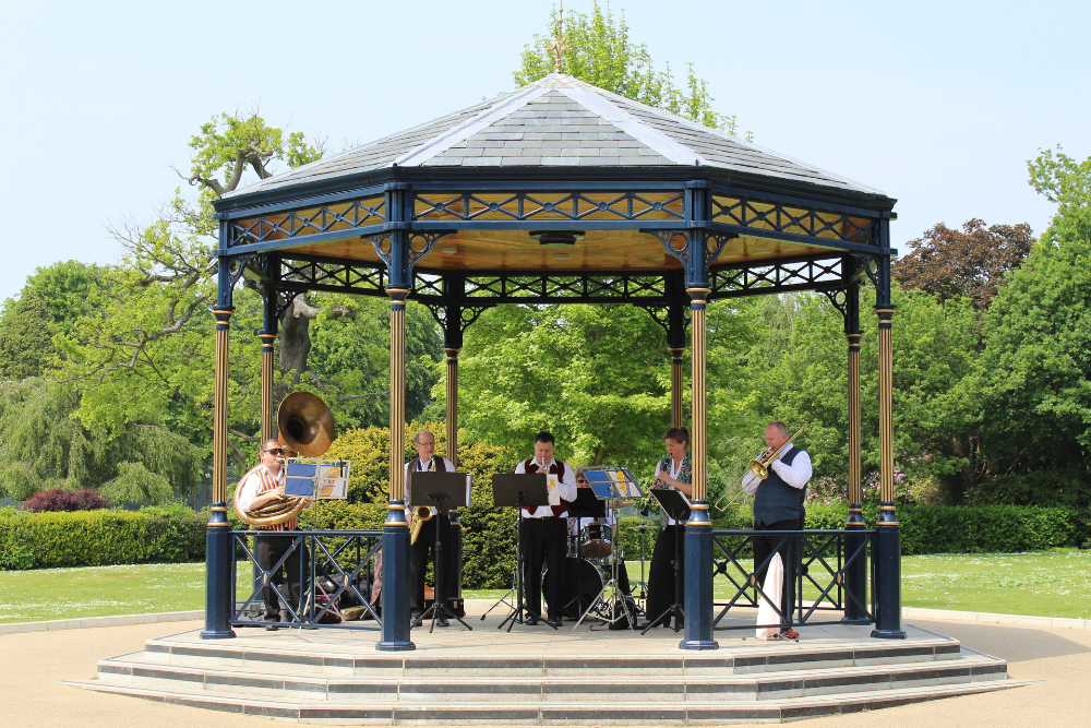 Brass band playing underneath the canopy of the Bandstand in Woking Park
