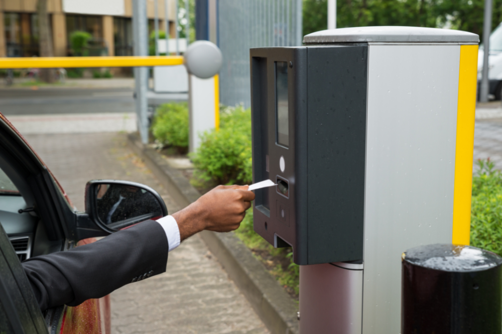 Image of a man's arm putting a parking ticket into a machine at the car park barrier exit