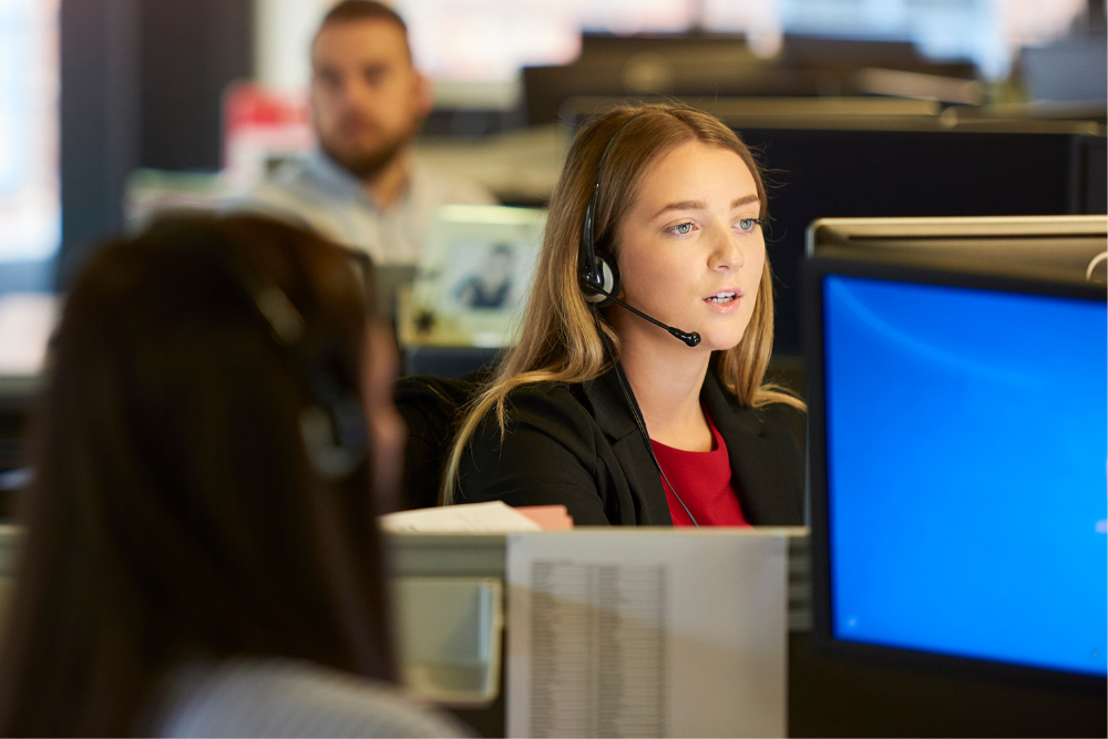 Close up of a female wearing a telephone headset in a call centre setting.