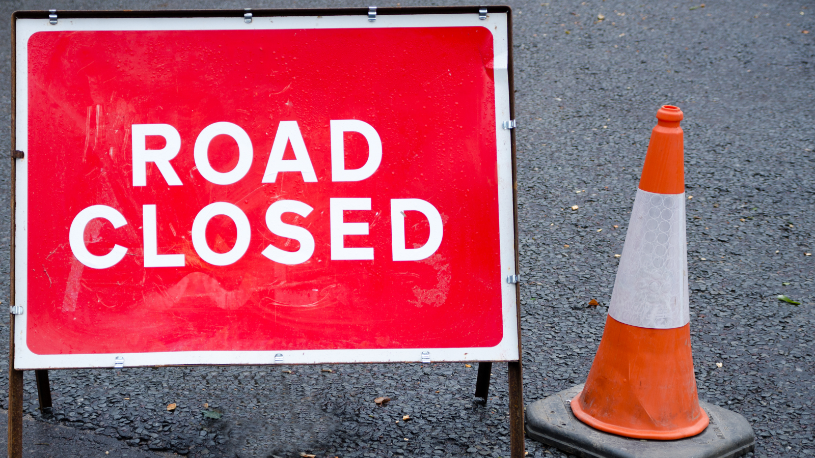 Image of red road closure sign and traffic cone
