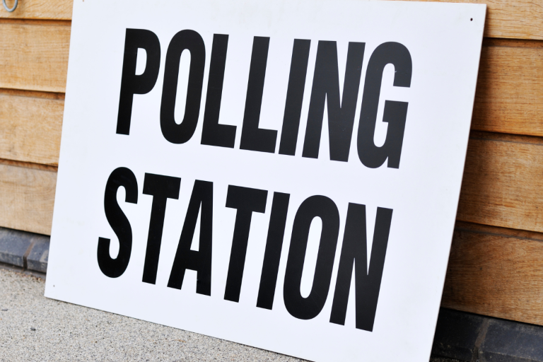 White sign with the words 'polling station' displayed on a wooden slatted background.