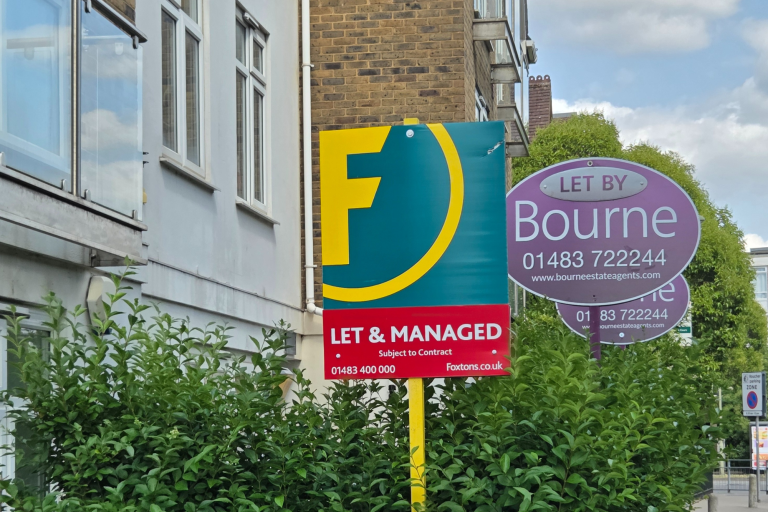 Two letting agent boards displayed outside a block of flats.