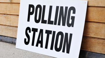 White sign with the words 'polling station' displayed on a wooden slatted background.