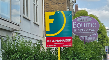 Two letting agent boards displayed outside a block of flats.