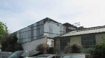 large front canopied enclosure made of scaffolding poles, corrugated metal sheeting, composite panels and a metal gate
