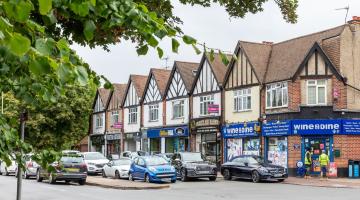 Parade of shops in Byfleet village with car parks in front.